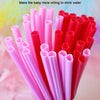 A close-up view of a large pack of heart-shaped pink disposable straws in various shades of pink and red.
