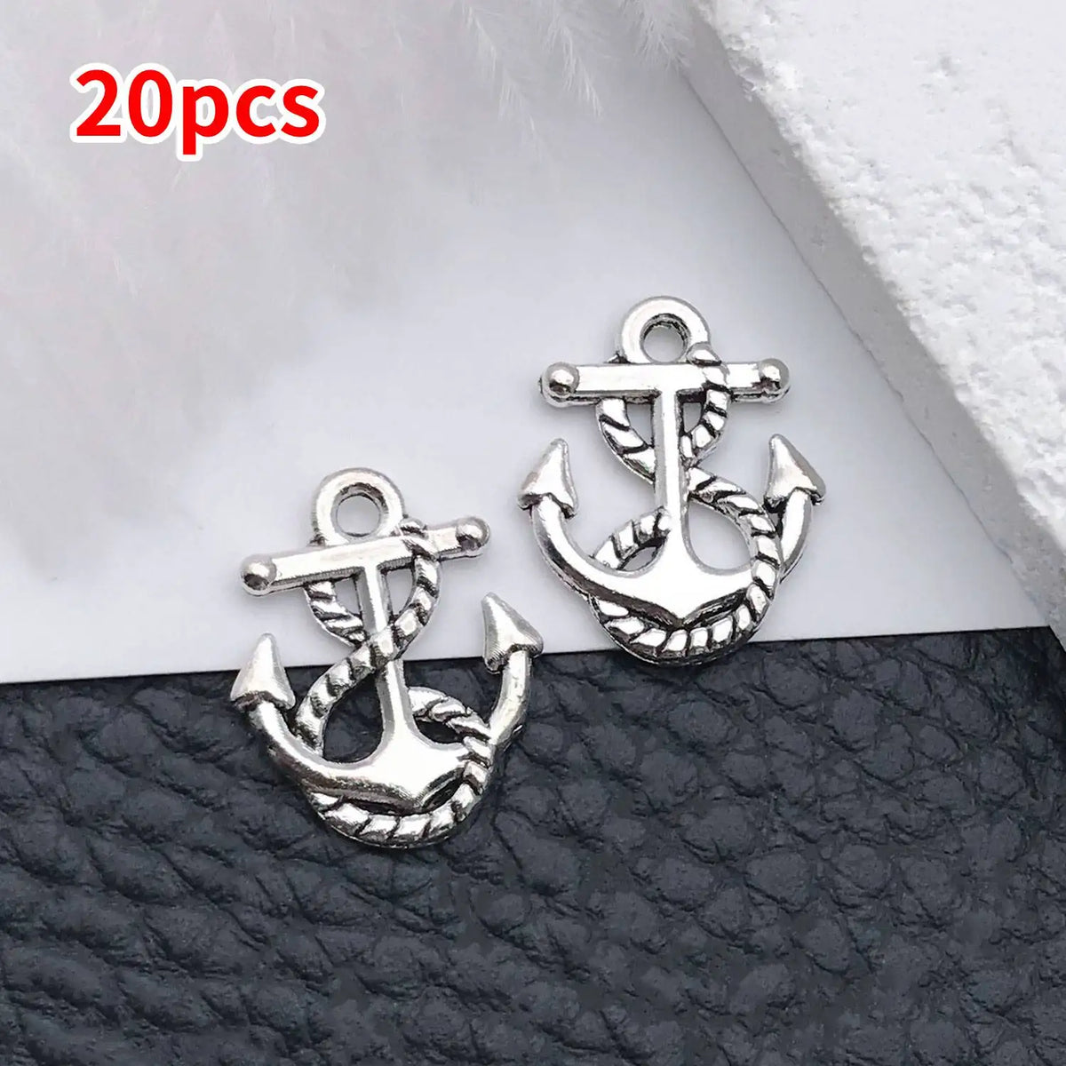 20 pieces of vintage ship anchor charms for jewelry making displayed on a dark surface.