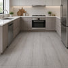 Modern kitchen featuring light wood grain flooring and gray cabinetry with a stainless steel range hood and backsplash.