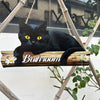 A black cat with yellow eyes is featured on a rustic wooden hanging sign that reads Bathroom.