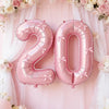 Pink foil number balloons spelling '20' decorated with pink floral garlands and sheer fabric