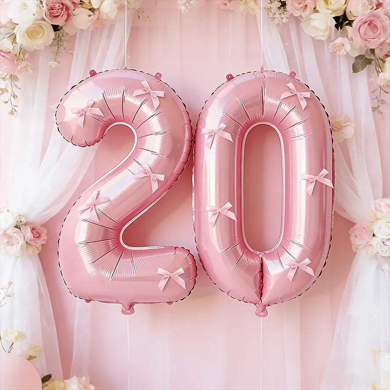 Pink foil number balloons spelling '20' decorated with pink floral garlands and sheer fabric