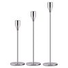 A set of three elegant metal candle holders with slender, polished silver-toned stems and round bases.