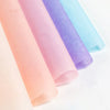 A stack of rolled soft tissue paper sheets in pastel shades of pink, purple, and blue.