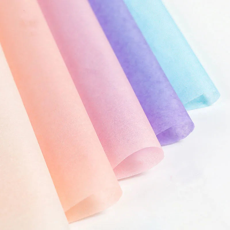 A stack of rolled soft tissue paper sheets in pastel shades of pink, purple, and blue.