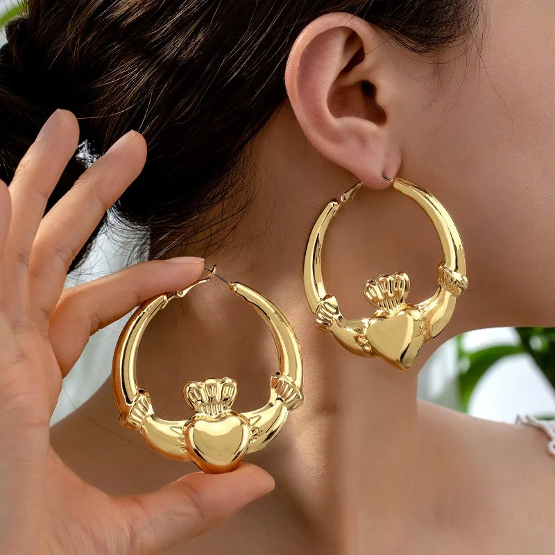A close-up of a person wearing oversized gold bamboo hoop earrings.