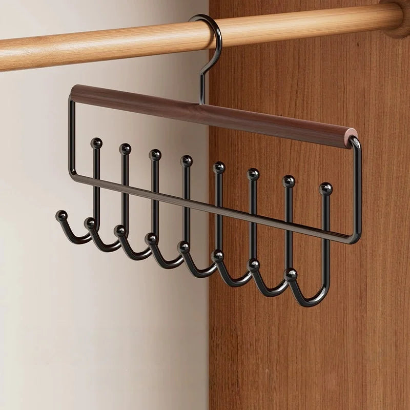 A wall-mounted metal coat rack with a wooden bar and eight hooks is displayed on a wooden panel.