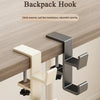 A close-up of a beige backpack hook installed on a wooden desk surface.