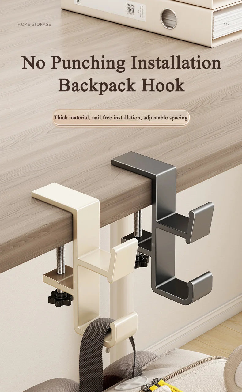 A close-up of a beige backpack hook installed on a wooden desk surface.