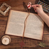 Marcador de Biblia de cuero PU con un diseño de Jesús como pastor, apoyado en un libro abierto.