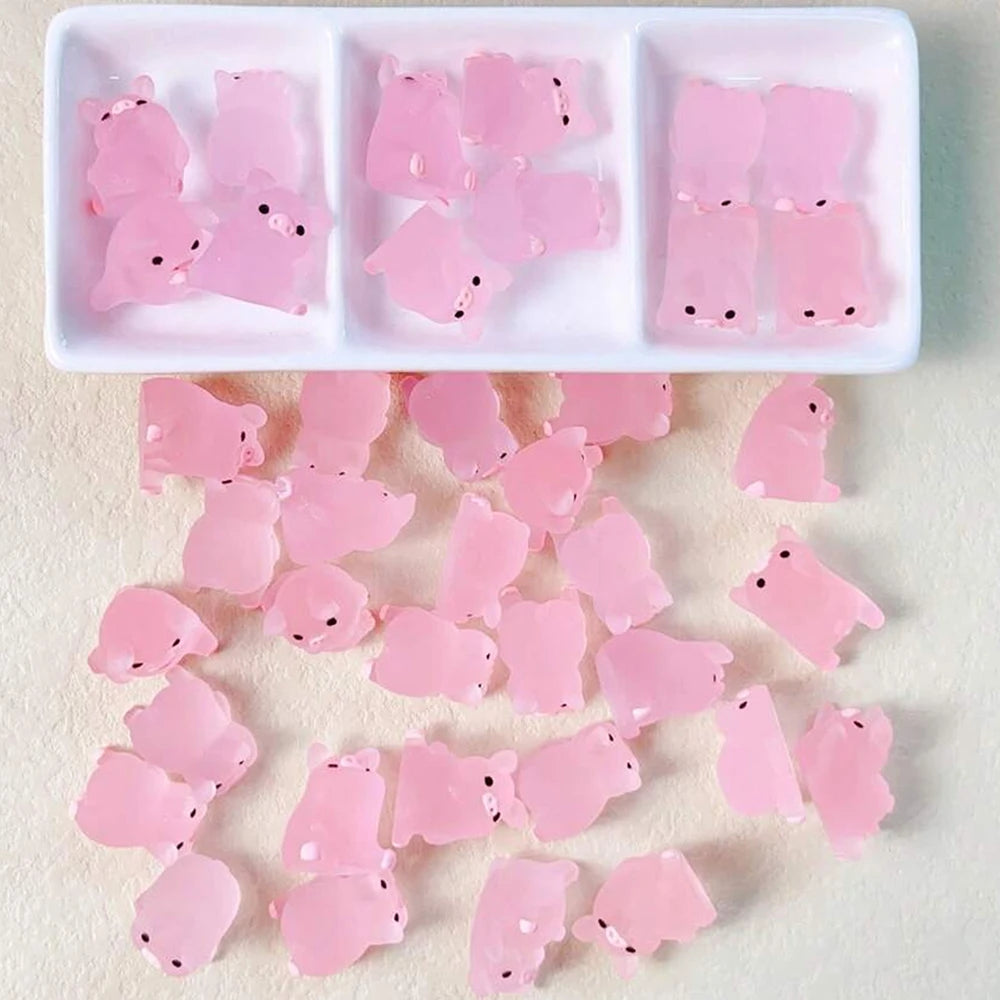 A white tray holds several pink glow-in-the-dark resin pig decorations.