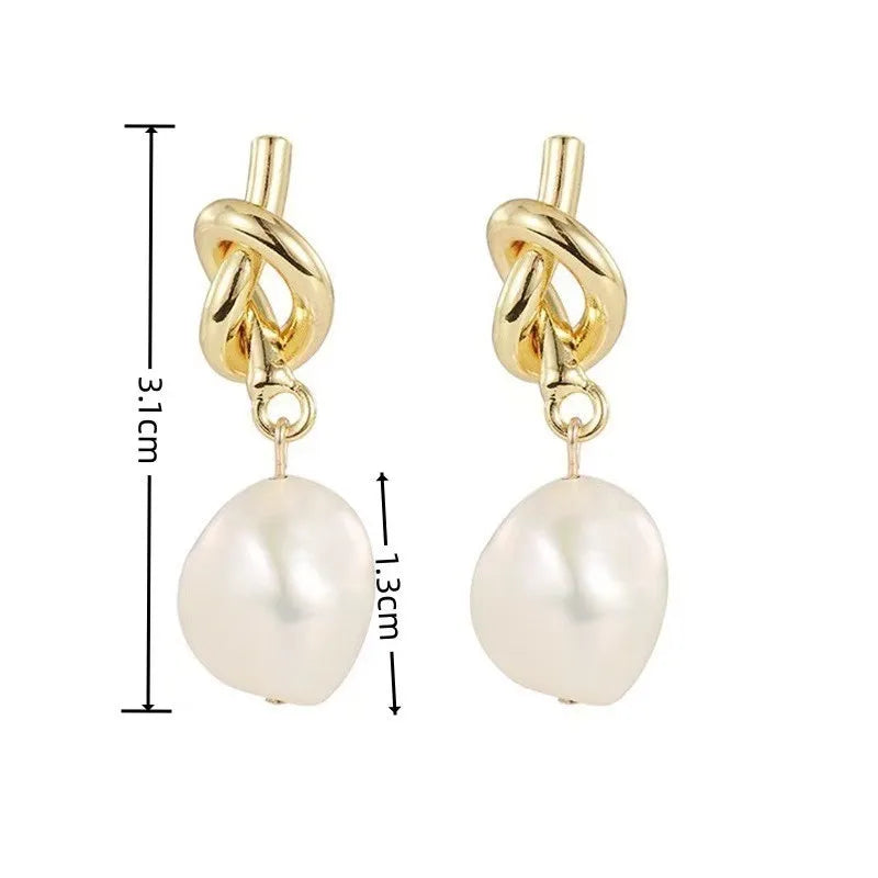 Elegant gold bean spliced pearl drop earrings with a twisted link and a round pearl drop.