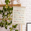 A magnetic poster frame displaying the English alphabet in pink lettering, mounted on a wooden rack.