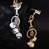 A golden dice keychain with a lucky charm design attached to a black quilted bag.