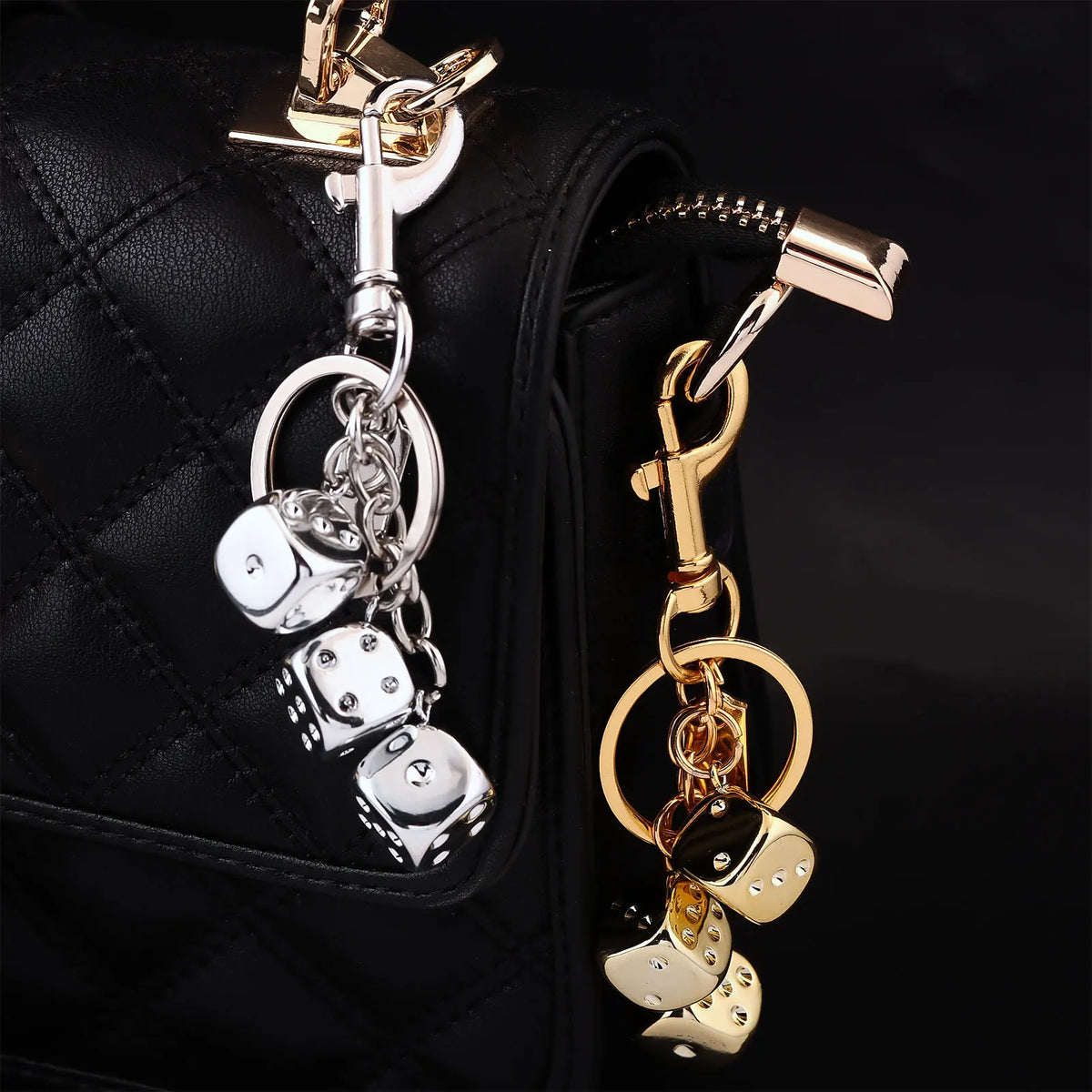 A golden dice keychain with a lucky charm design attached to a black quilted bag.