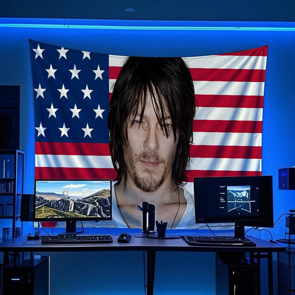 A man with long dark hair looks at a large American flag banner displayed on a blue background.