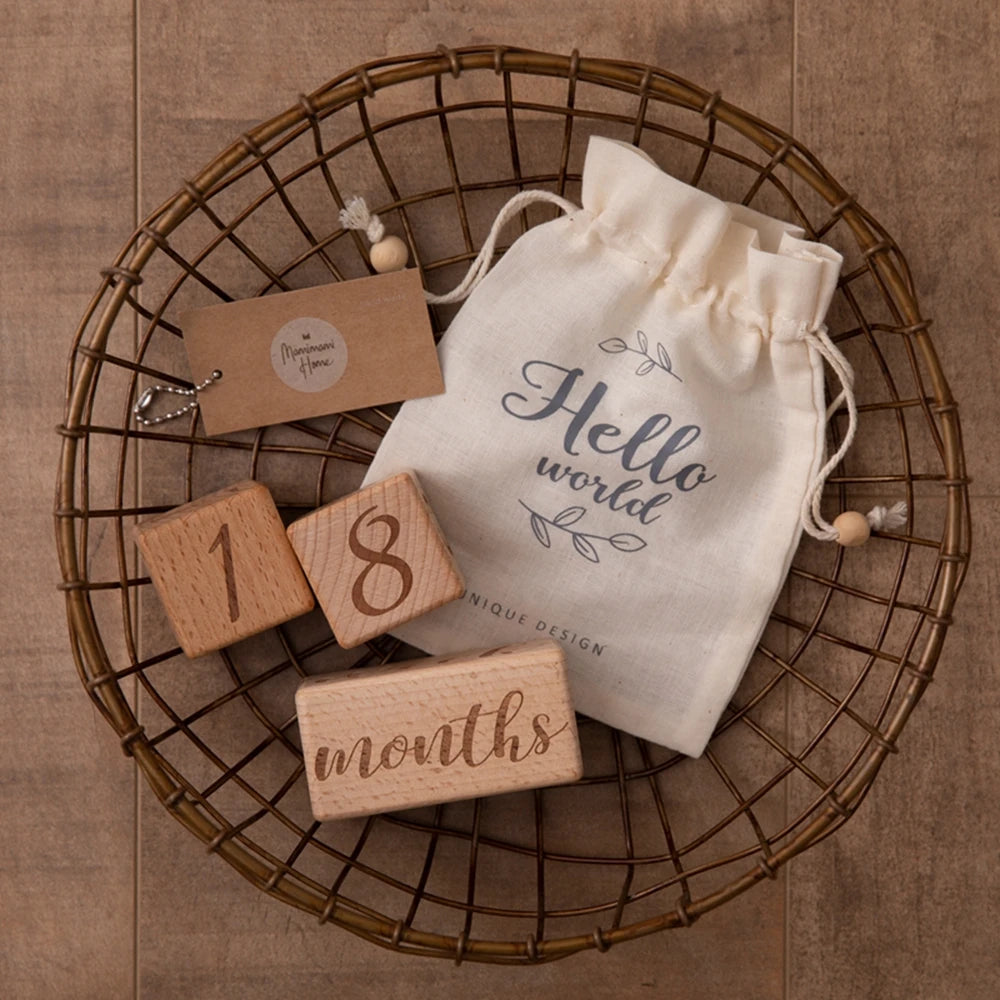 A bundle of wooden baby milestone cards and a natural linen drawstring bag displayed on a woven tray.