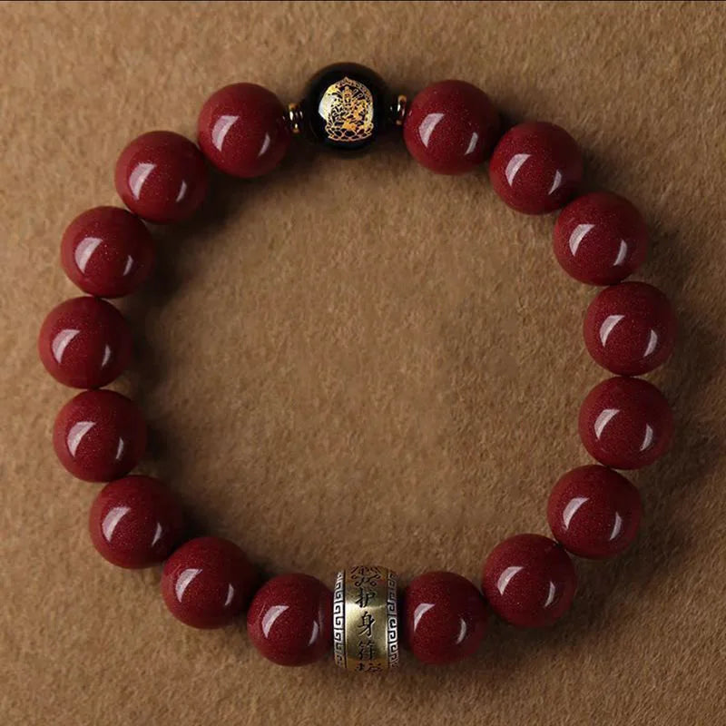 A bracelet made of polished red cinnabar stones and a dark bead, worn on a brown surface.