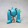 A blue Hatsune Miku anime figurine with long blue hair and a green accessory.