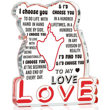 A clear glass ornament shaped like a heart with red lettering that says I choose you to love.