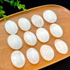 Several smooth, translucent white selenite palm crystals are arranged on a wooden tray.
