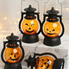 A set of black pumpkin lanterns with glowing orange LED faces displayed on a white marble surface.