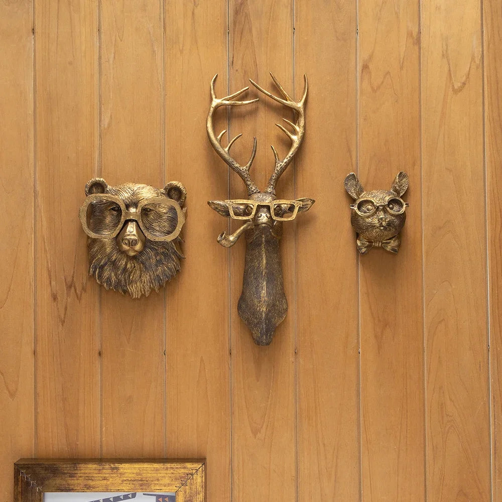 A set of bronze deer head storage hooks and wall decor mounted on a wooden surface.