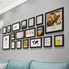 A gallery wall display featuring multiple framed pictures with nature and inspirational quotes on a gray wall.