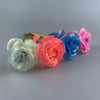 A collection of colorful, glowing gold foil roses in shades of pink, blue, and white arranged horizontally.