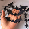 A hand holds black bat-shaped wall decals with glowing LED lights.