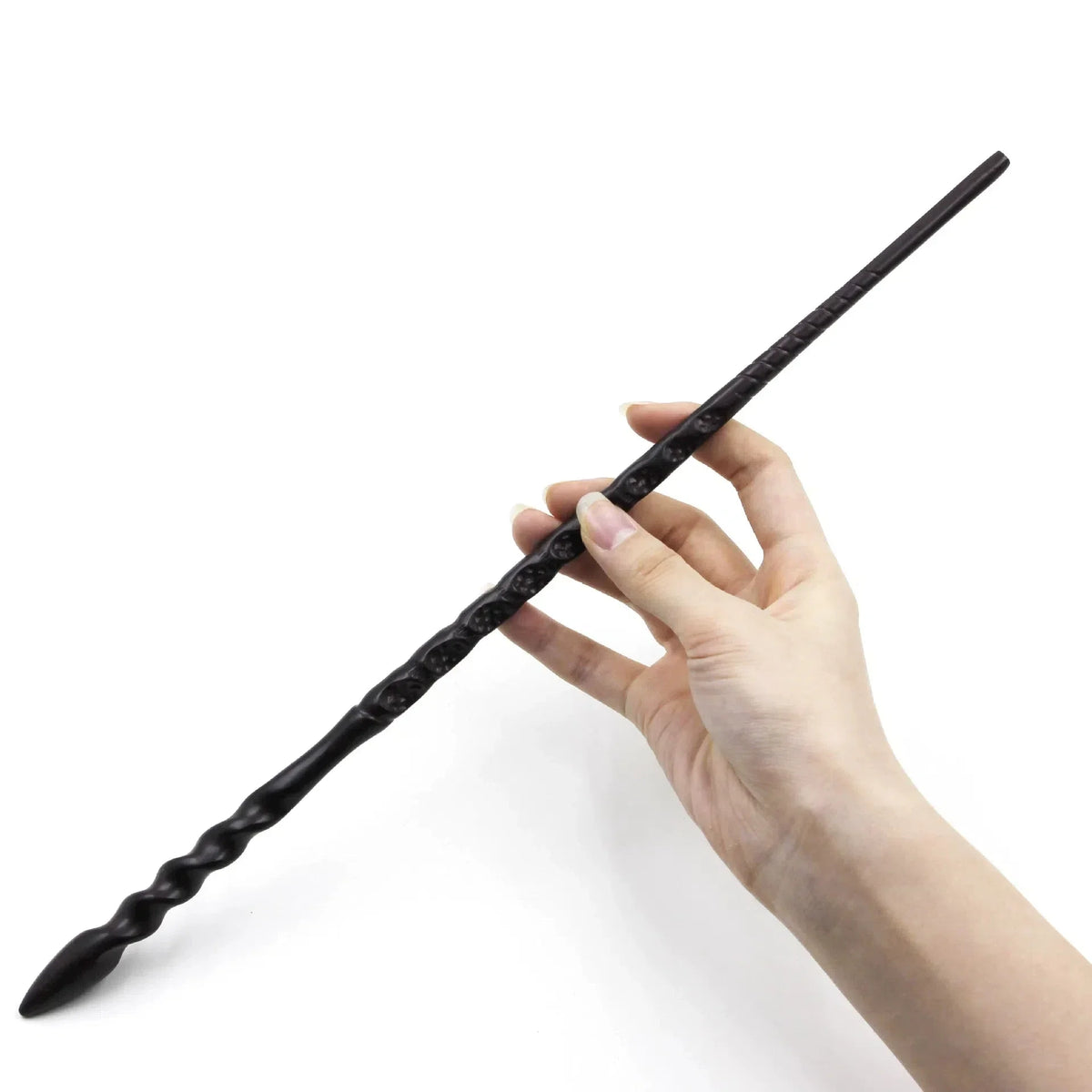 A hand holds a long, black, twisted metal magic wand against a white background.