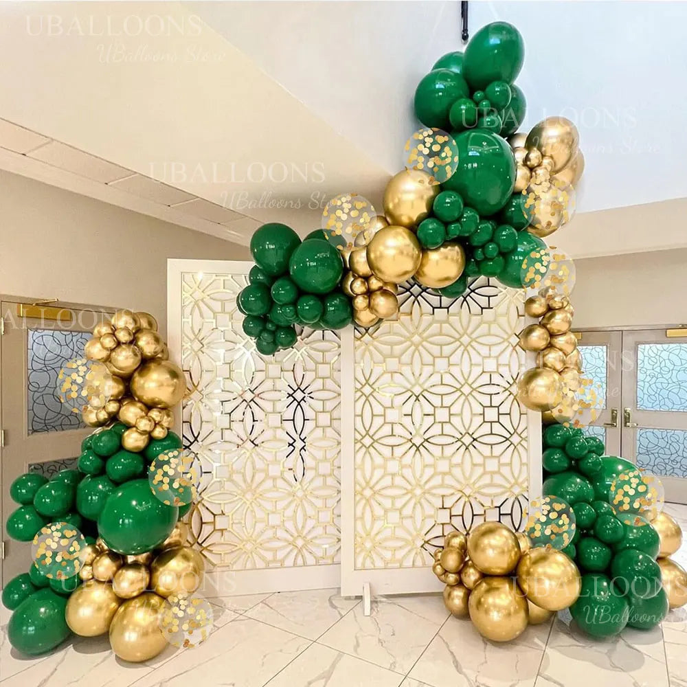 A display of chrome gold and dark green balloons arranged in a floral archway for an event.