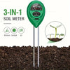 A green 3-in-1 soil meter with three probes inserted into dark soil, used for measuring moisture, sunlight, and pH.