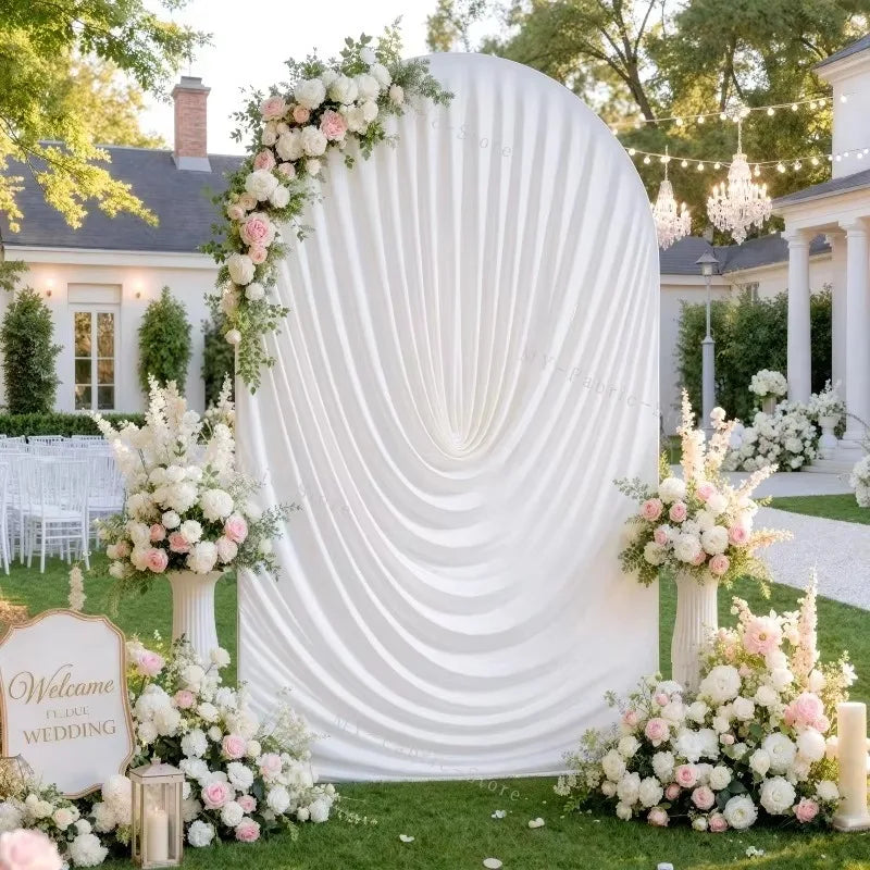 A white spandex arch cover decorated with pink and white flowers for a wedding backdrop.