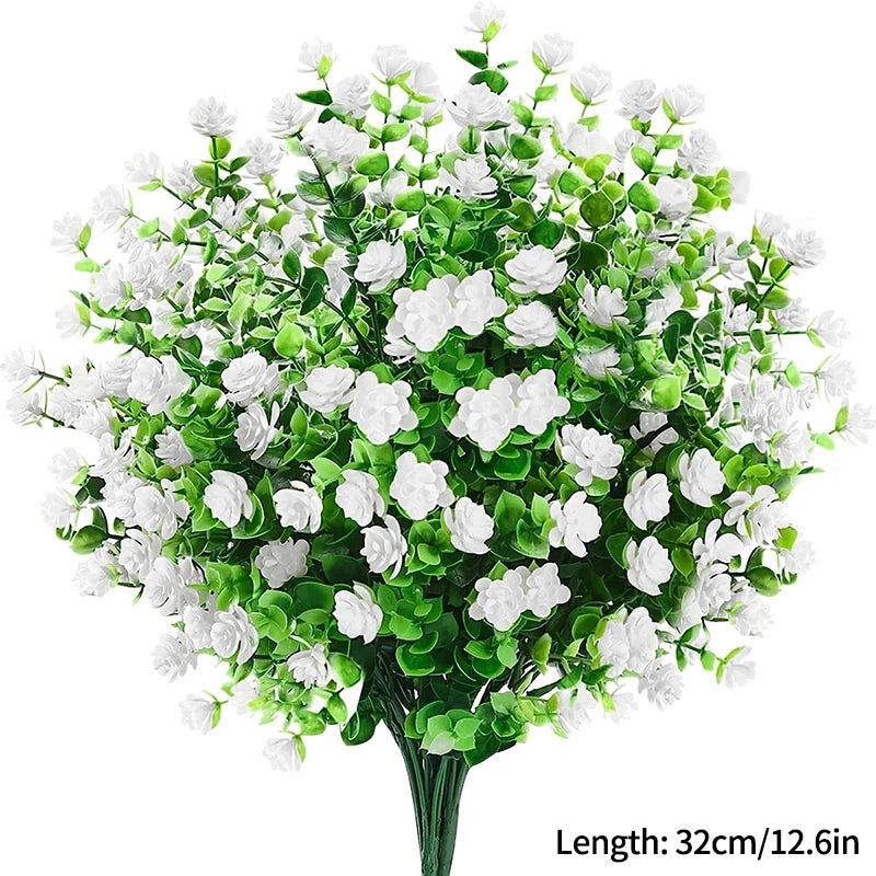 Un bouquet de fleurs blanches artificielles avec des feuilles vertes.