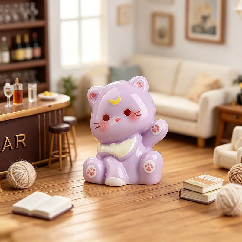 A purple resin cat keychain sitting on a wooden floor next to a book.
