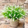 A potted artificial lavender plastic wreath with bright green foliage and white flowers sits on a stone surface.
