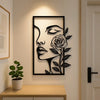 A black silhouette of a woman's face and rose on a wall, displayed above a wooden surface.