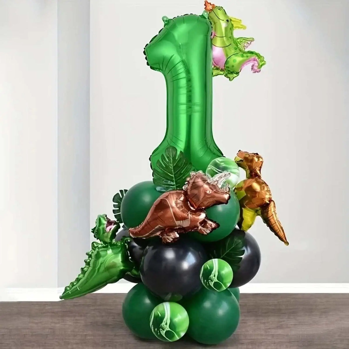 A set of green and gold dinosaur-themed balloons, including a large number one balloon.