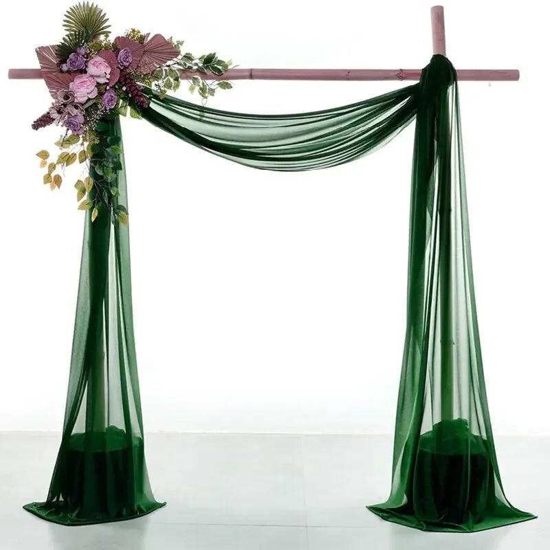 Two panels of sheer green chiffon fabric draped to form a wedding arch backdrop.