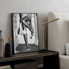 A black and white art print featuring a woman in high heels, displayed on a television screen in a modern living room.