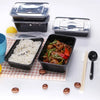 A set of black plastic food storage containers with lids, some containing rice and a meat dish, displayed on a white surface.