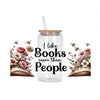 A glass jar filled with clear liquid and a straw, surrounded by floral arrangements and open books.