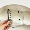 A hand holds a clear pastel macaron binder for K-Pop collectibles against a white wall.