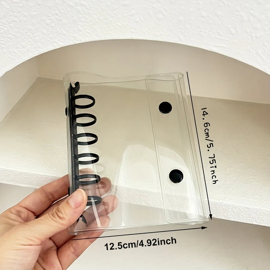 A hand holds a clear pastel macaron binder for K-Pop collectibles against a white wall.