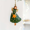 A vintage wood angel ornament with golden wings and a green dress featuring an orange star, hanging from a string.
