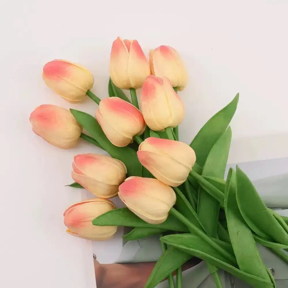 A bouquet of realistic artificial tulips in shades of peach and cream.