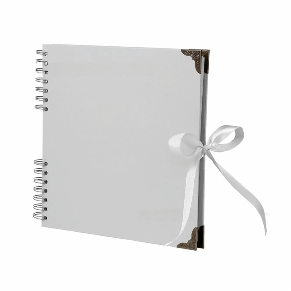 Bloc-notes d'album photo blanc à plat avec un fermoir doré décoratif et un ruban blanc attaché sur la couverture.