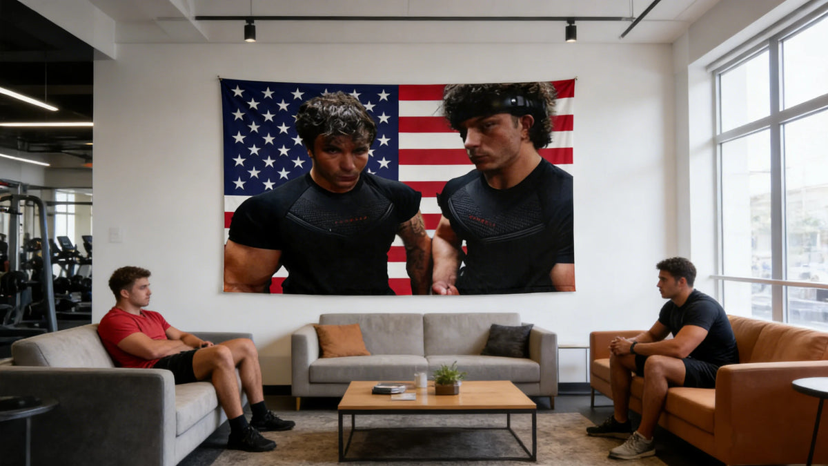 Two men in black shirts stand in front of an American flag backdrop in a gym setting.