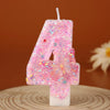 Pink glitter candle shaped like the number 4 with a butterfly design